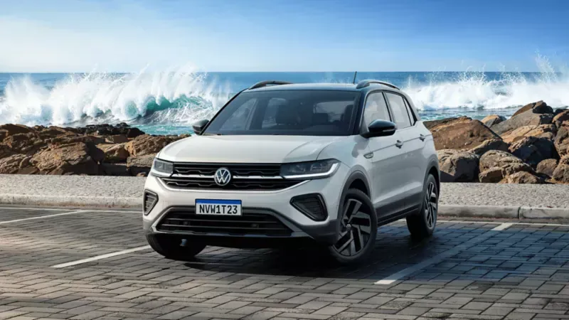 SUV Volkswagen Nivus vermelho estacionado em uma rua da cidade com palmeiras e prédios altos.