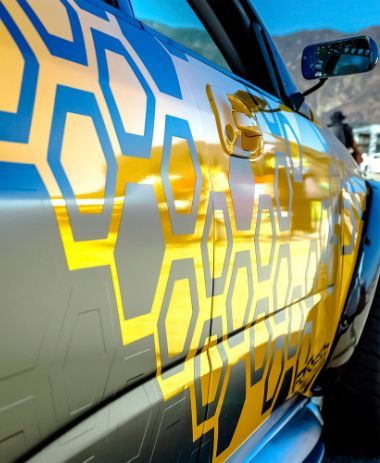 A car with a blue and yellow design on it Custom Signs & Signage by Fulham Signs 