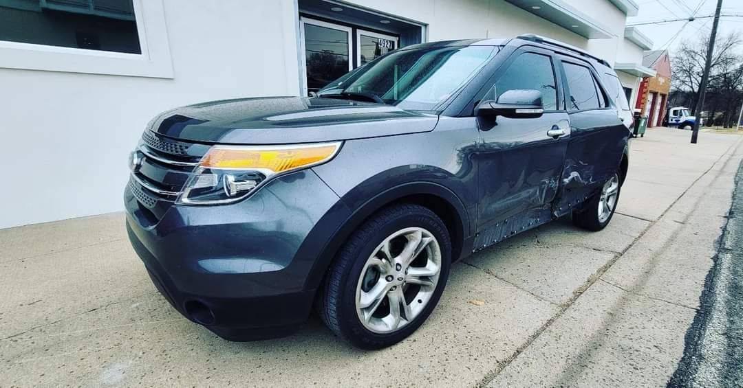Dark blue SUV parked on a sidewalk beside a building on a cloudy day