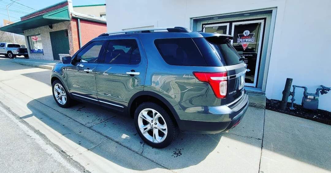 Dark gray SUV parked beside a white building in a sunny lot