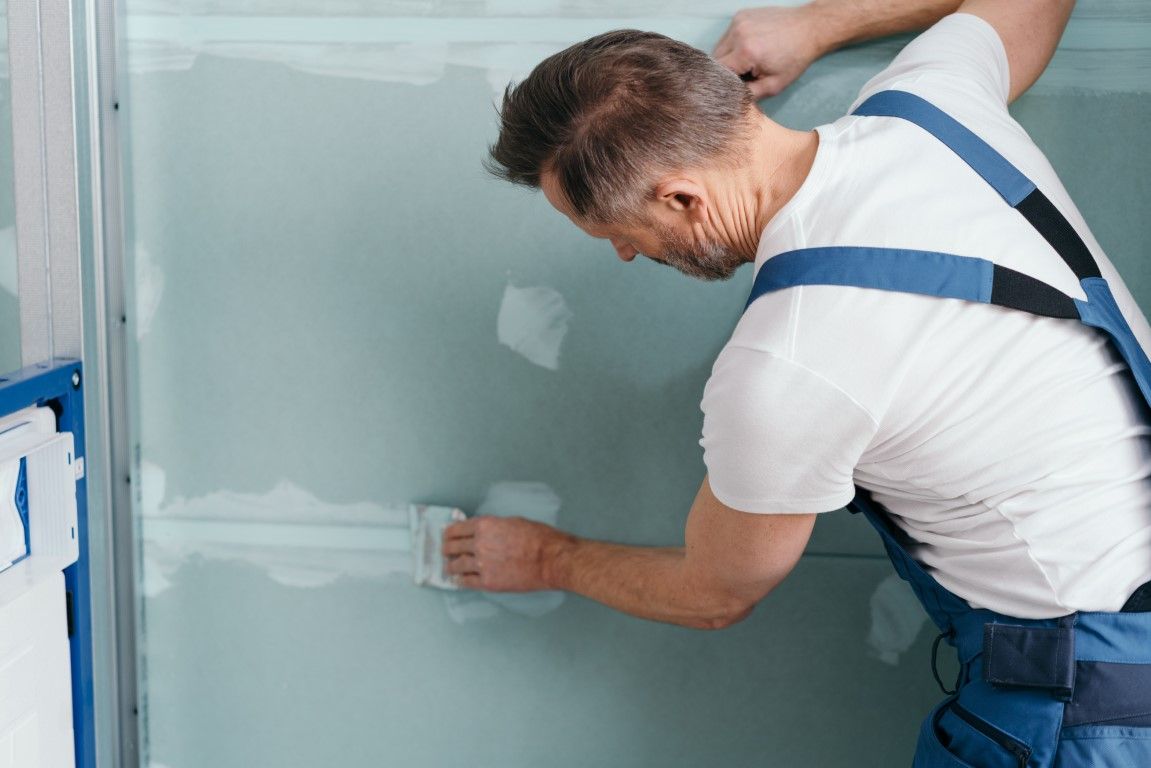 Worker smoothing plaster on a wall with a trowel in a construction setting