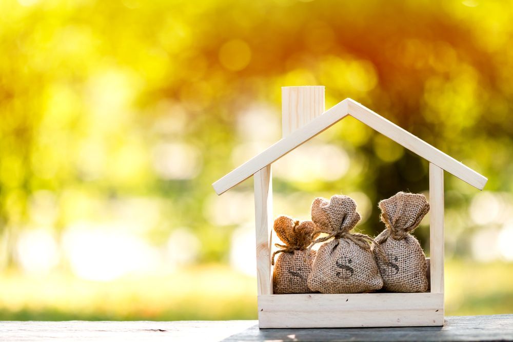 Wooden House Frame With Three Money Bags Inside — Peterson Property Valuations Brisbane in Caboolture, QLD