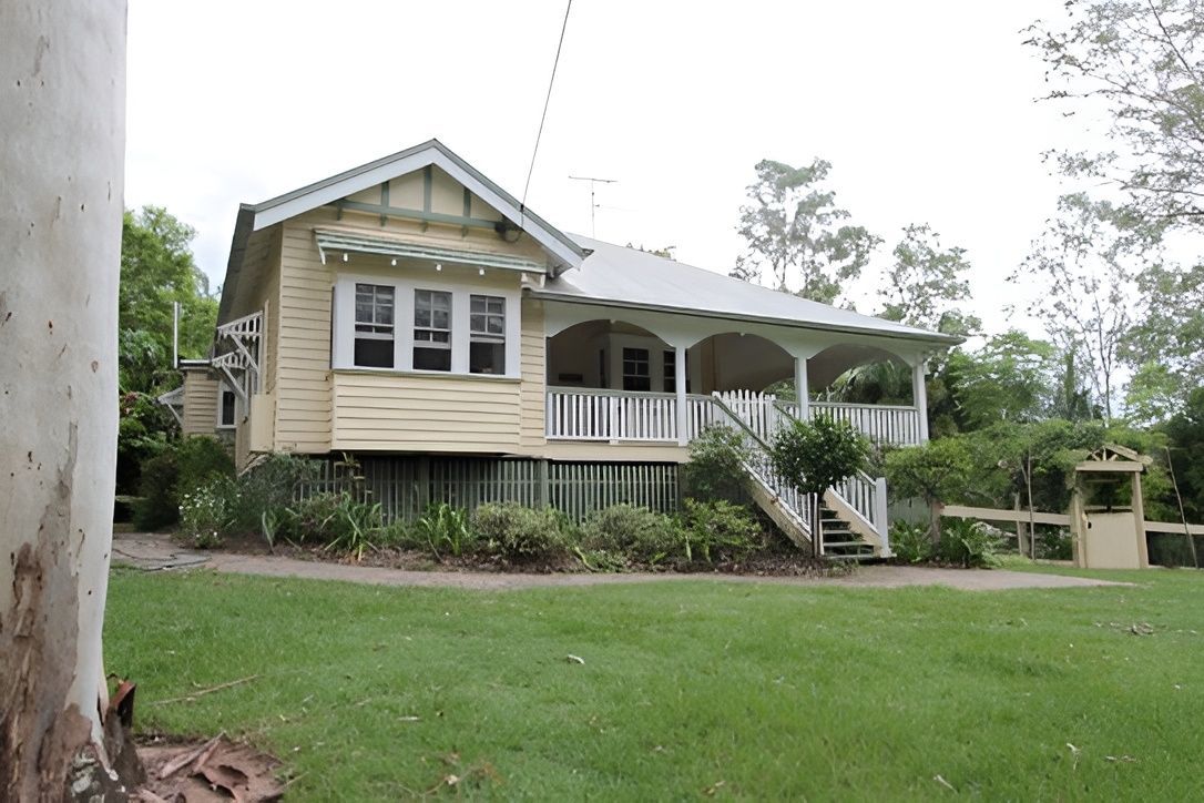 Yellow Wooden House With Porch, White Trim — Peterson Property Valuations Brisbane in Burleigh, QLD