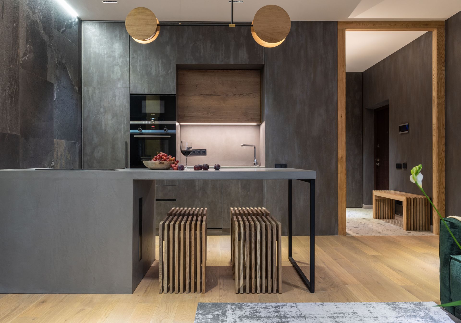 Modern kitchen with dark cabinets, stone island, striped stools, and warm pendant lights
