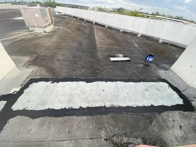 Rooftop with a large, rectangular section repaired with light concrete, bordered by dark sealant.