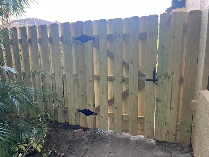 Wooden gate with black hardware in a yard.