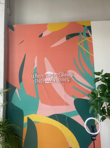 Wall mural with colorful tropical leaves and neon sign reading 