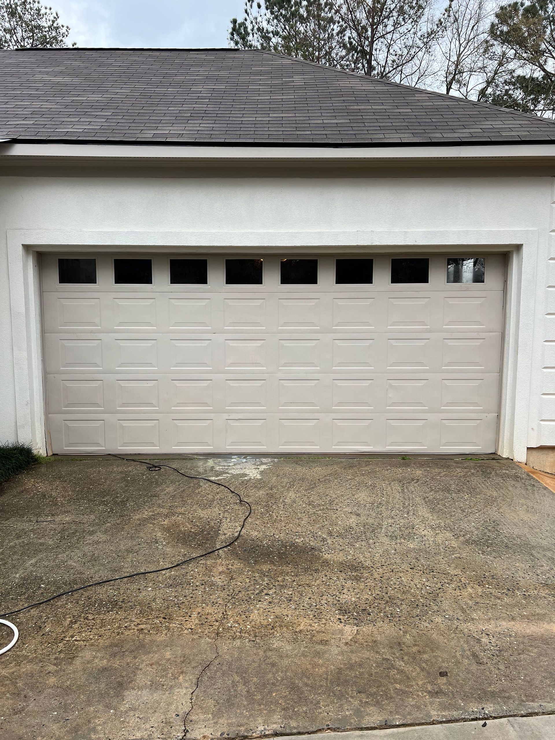 A white garage door is sitting in the driveway of a house after repaired