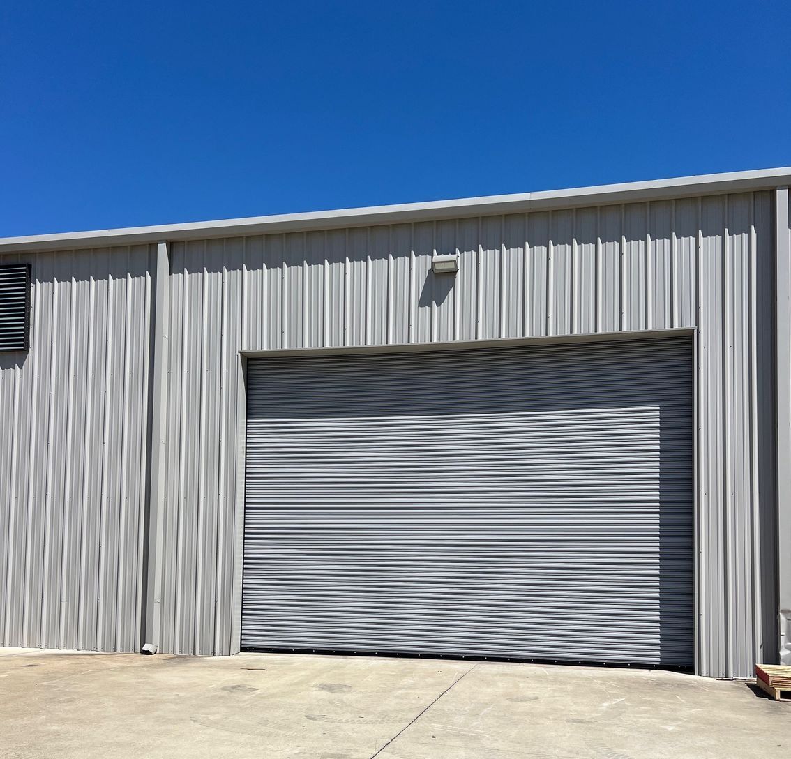 A building with a garage door and a blue sky in the background