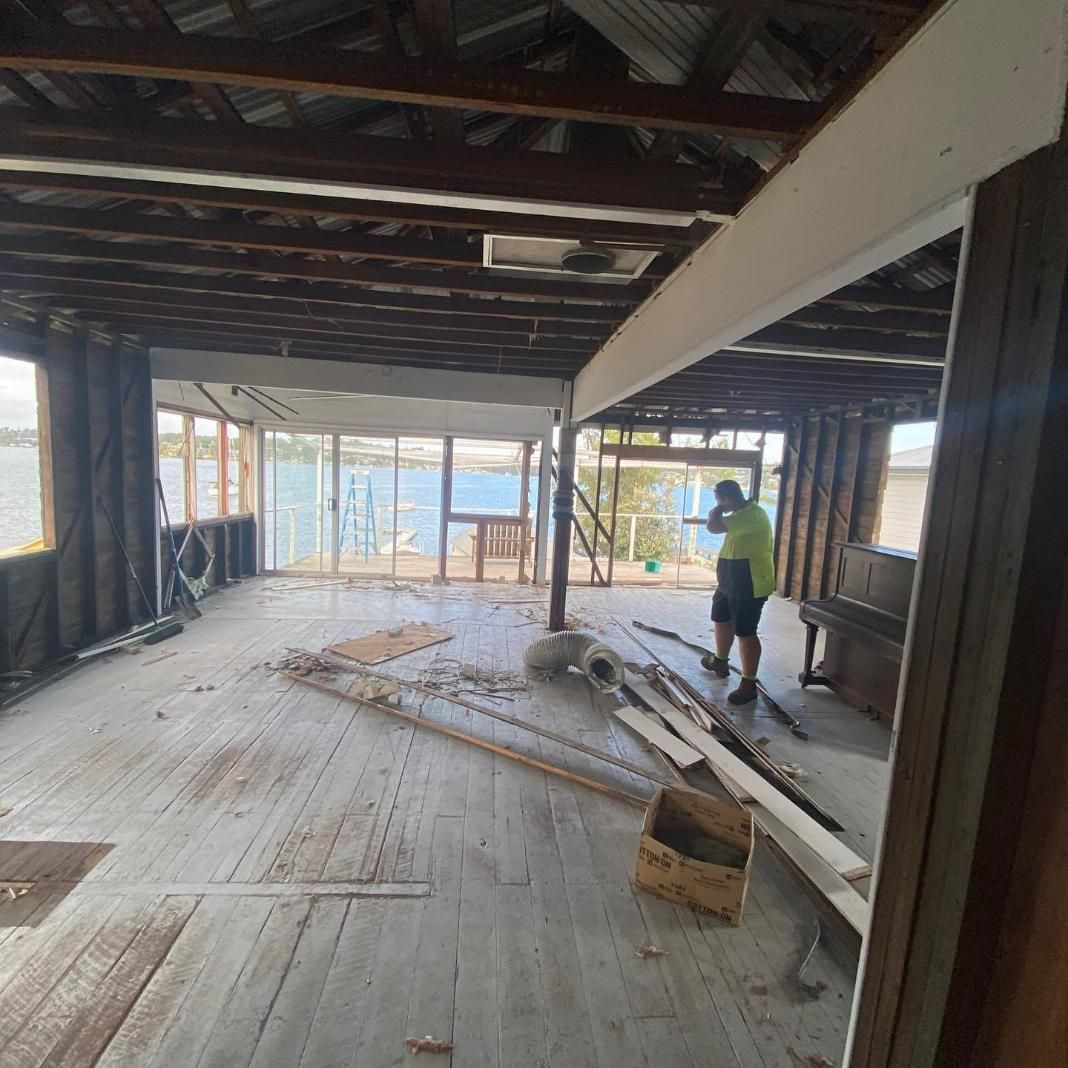 A Man Is Standing in The Middle of A Large Room with Wooden Floors — Jonobilt in Caves Beach, NSW