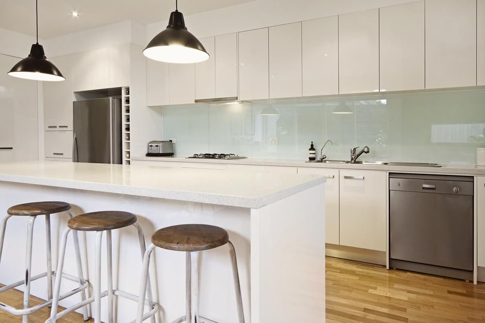 A Kitchen with White Cabinets, Stools, a Refrigerator and A Dishwasher — Jonobilt in Warners Bay, NSW