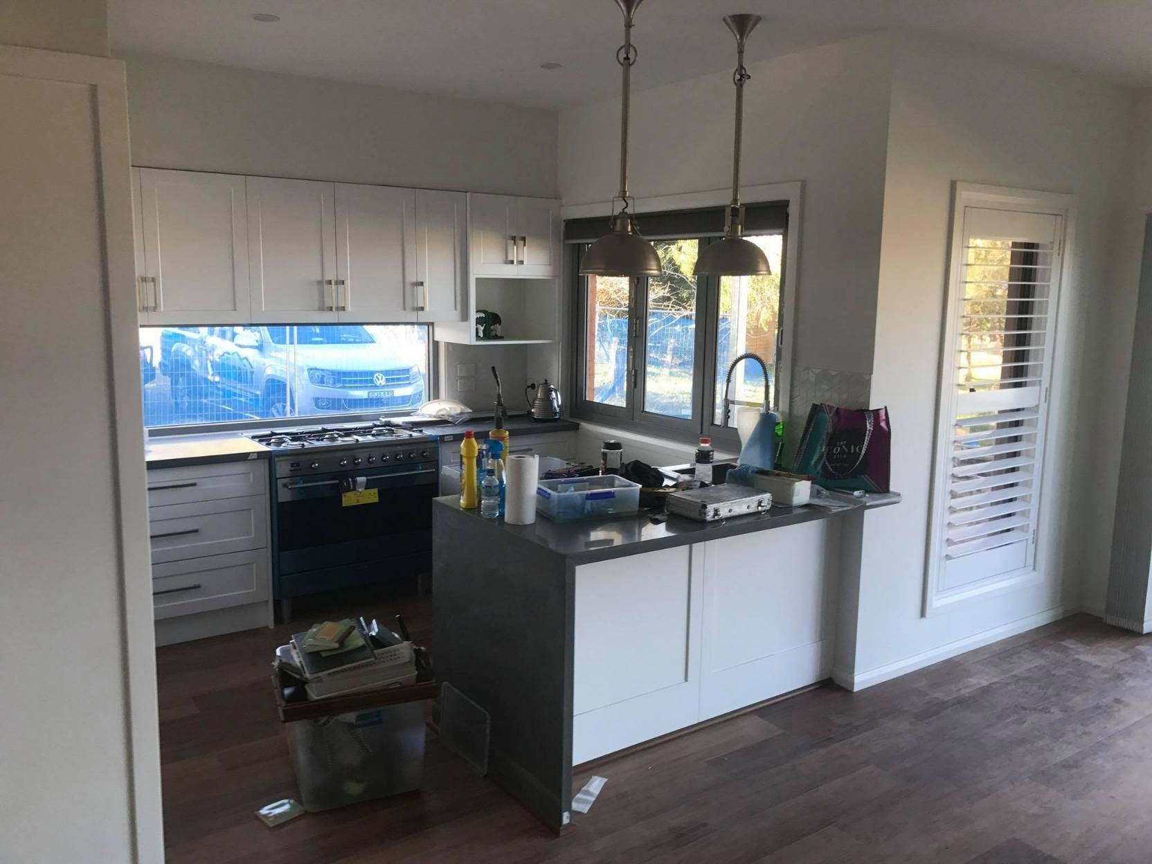 A Kitchen with White Cabinets and A Large Island in The Middle of The Room — Jonobilt in Kotara, NSW