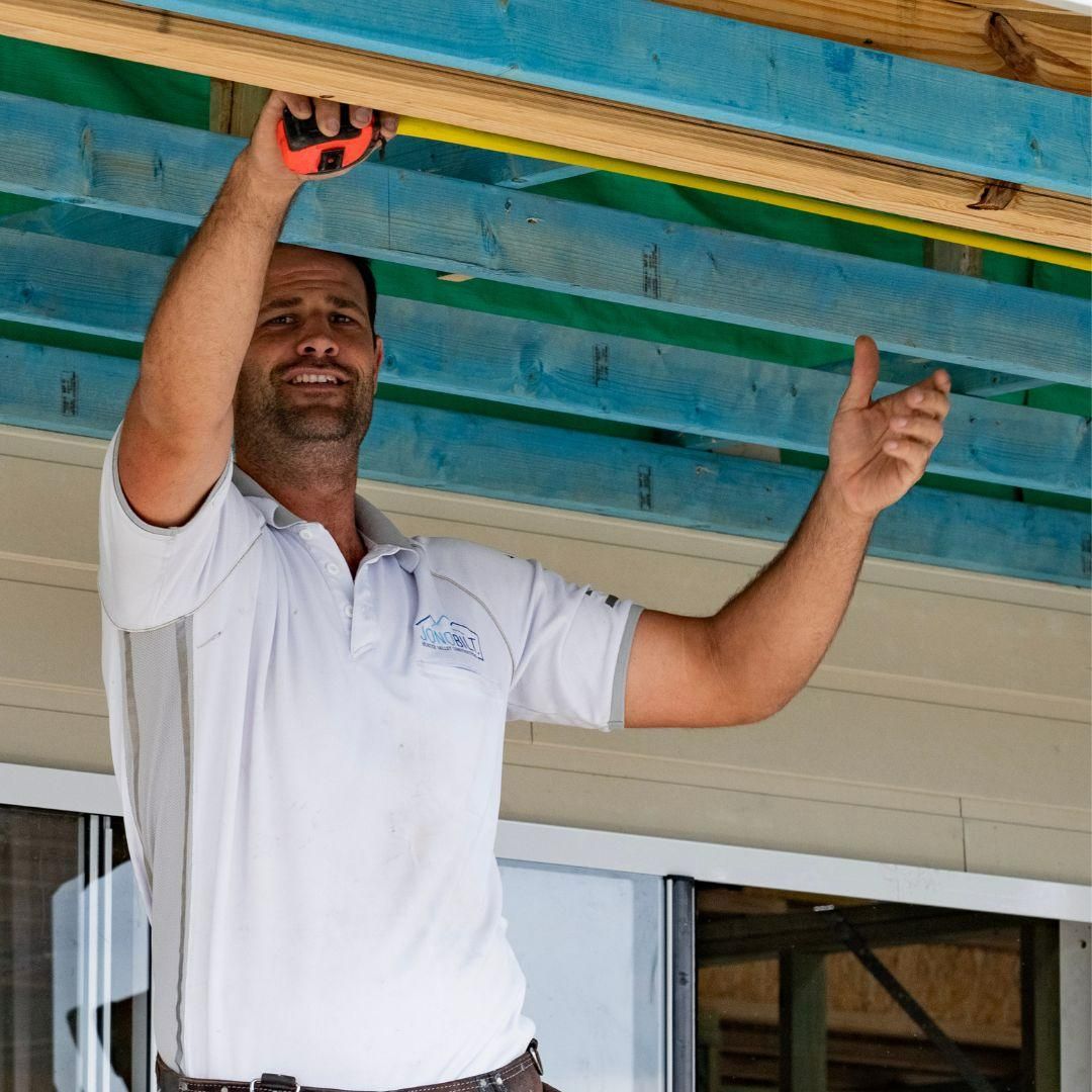 A Man Is Measuring a Ceiling with A Tape Measure โ Jonobilt in Bolwarra, NSW