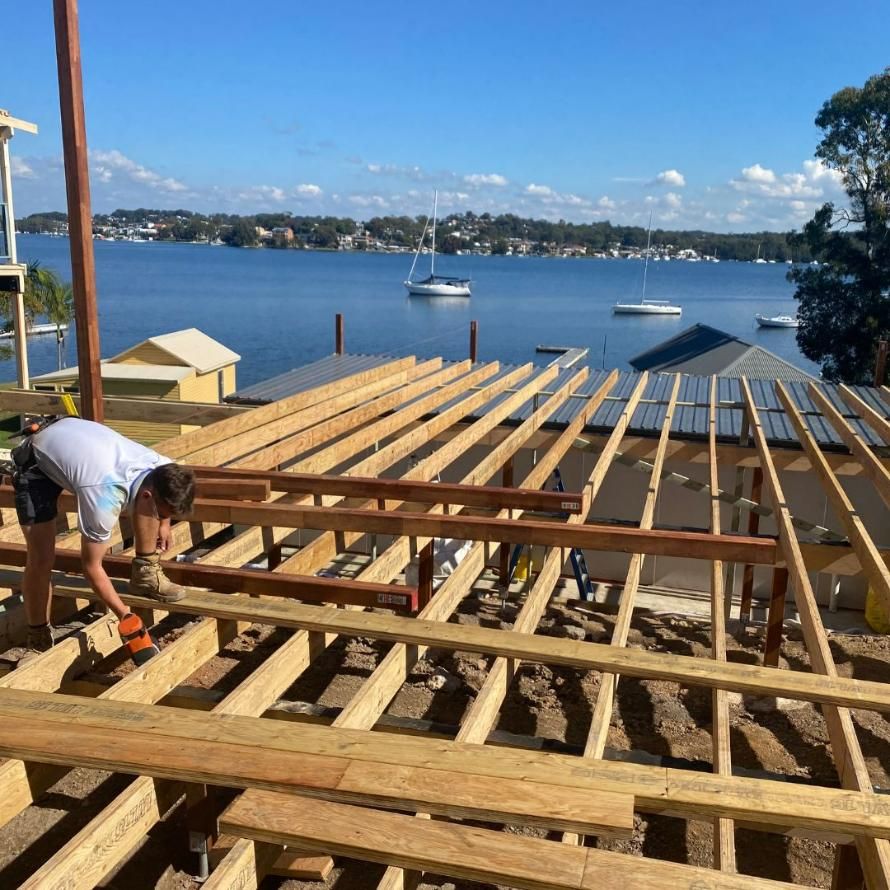 A Man Is Working on A Wooden Deck Overlooking a Body of Water — Jonobilt in Kotara, NSW