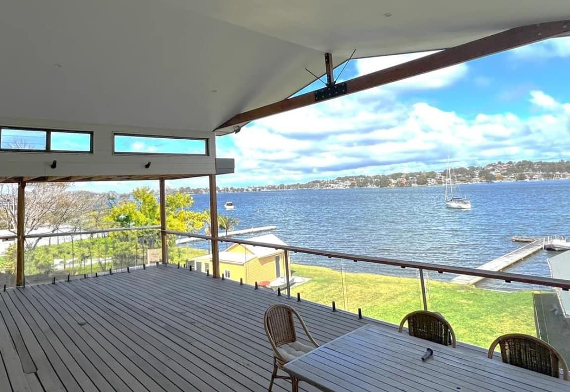 A Large Deck with A Table and Chairs Overlooking a Body of Water — Jonobilt in Cameron Park, NSW