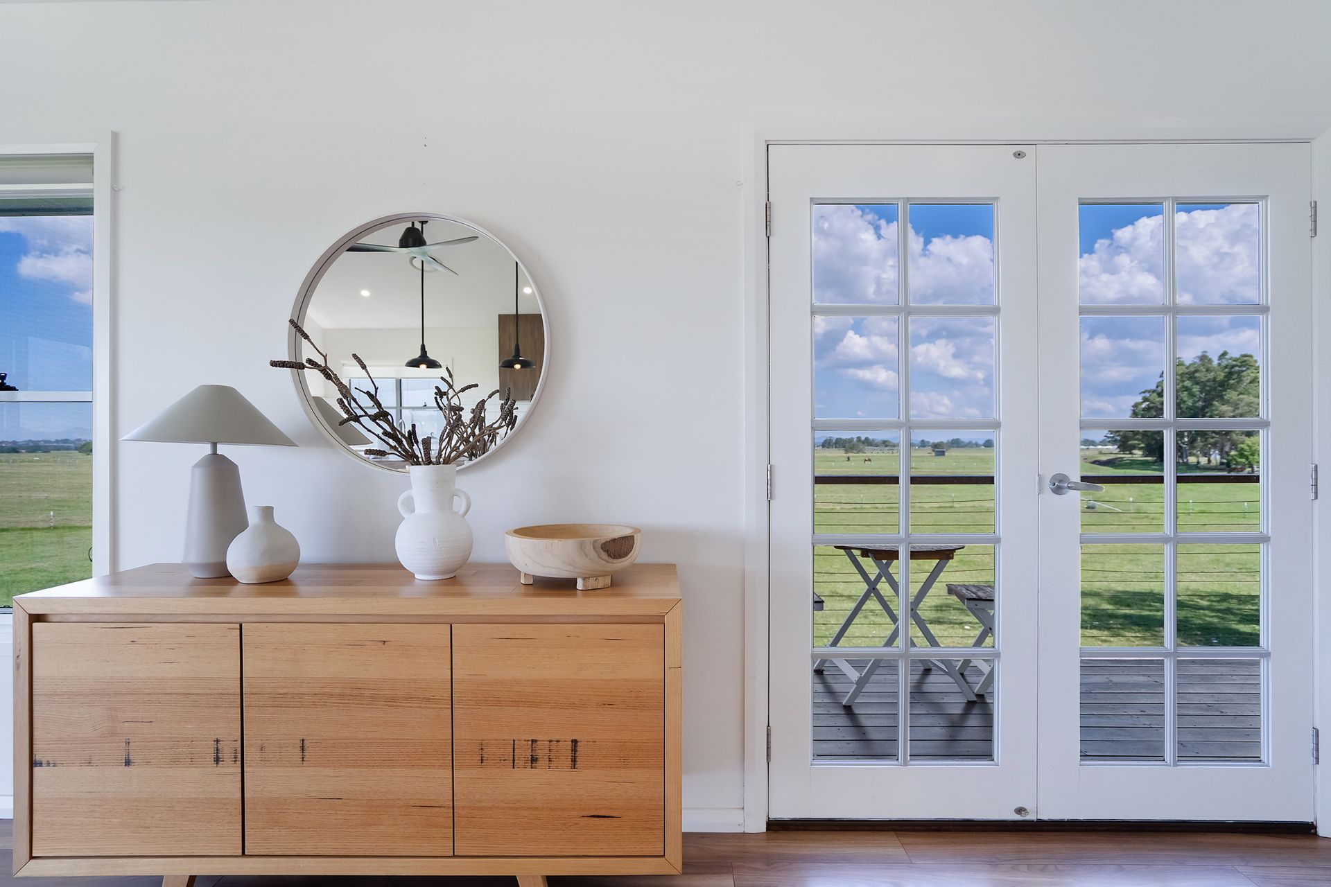 A light wooden entertainment unit in front of glass window doors — Jonobilt in Bolwarra, NSW