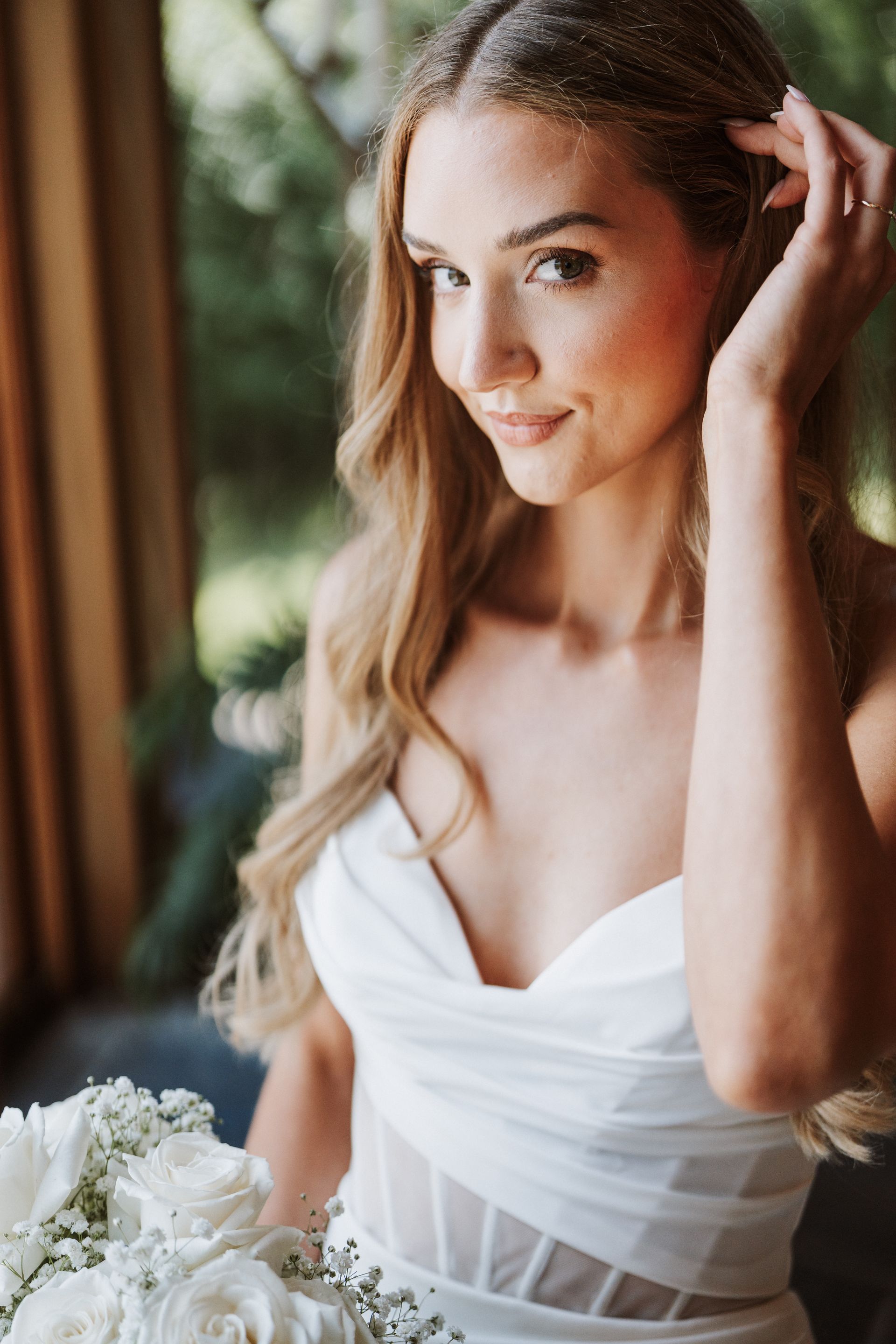 The bride is wearing a white dress and holding a bouquet of white roses.