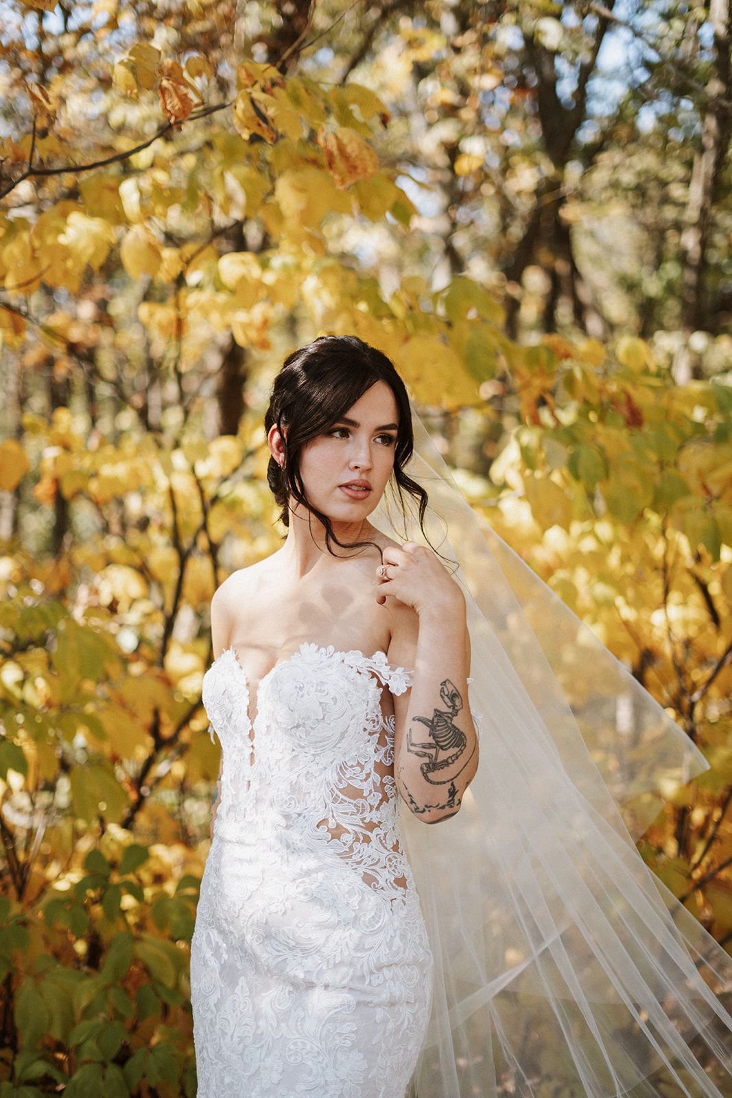A woman in a wedding dress and veil is standing in the woods.