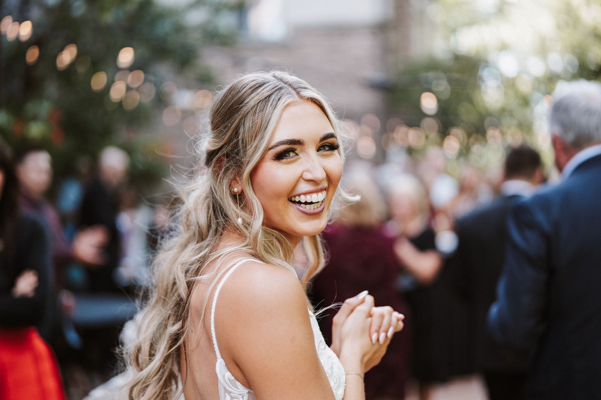 A bride in a wedding dress is smiling in front of a crowd of people.