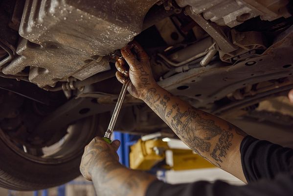 Mechanic tightening a bolt under a car on a lift with a wrench