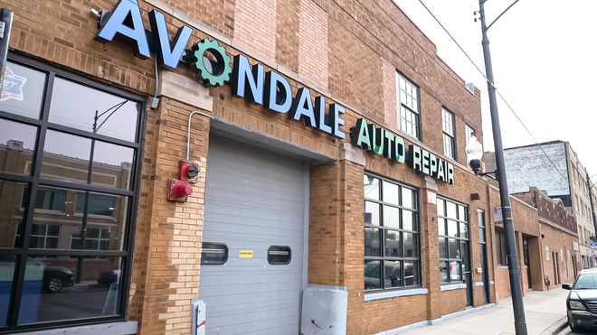 Avenue Auto Rent storefront with brick exterior, large windows, and a gray garage door on a city street