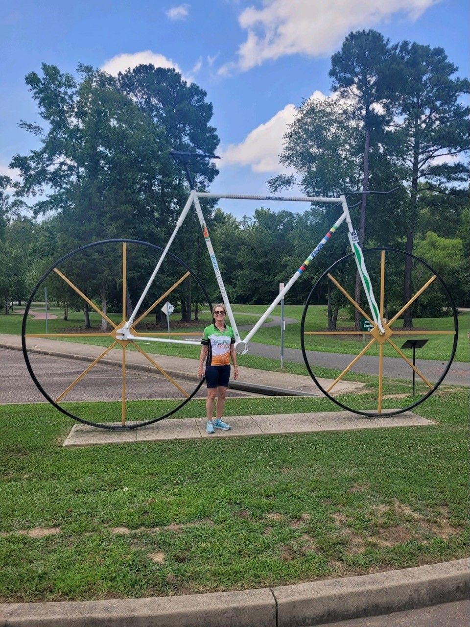 A girl is standing in front of a large bicycle statue.