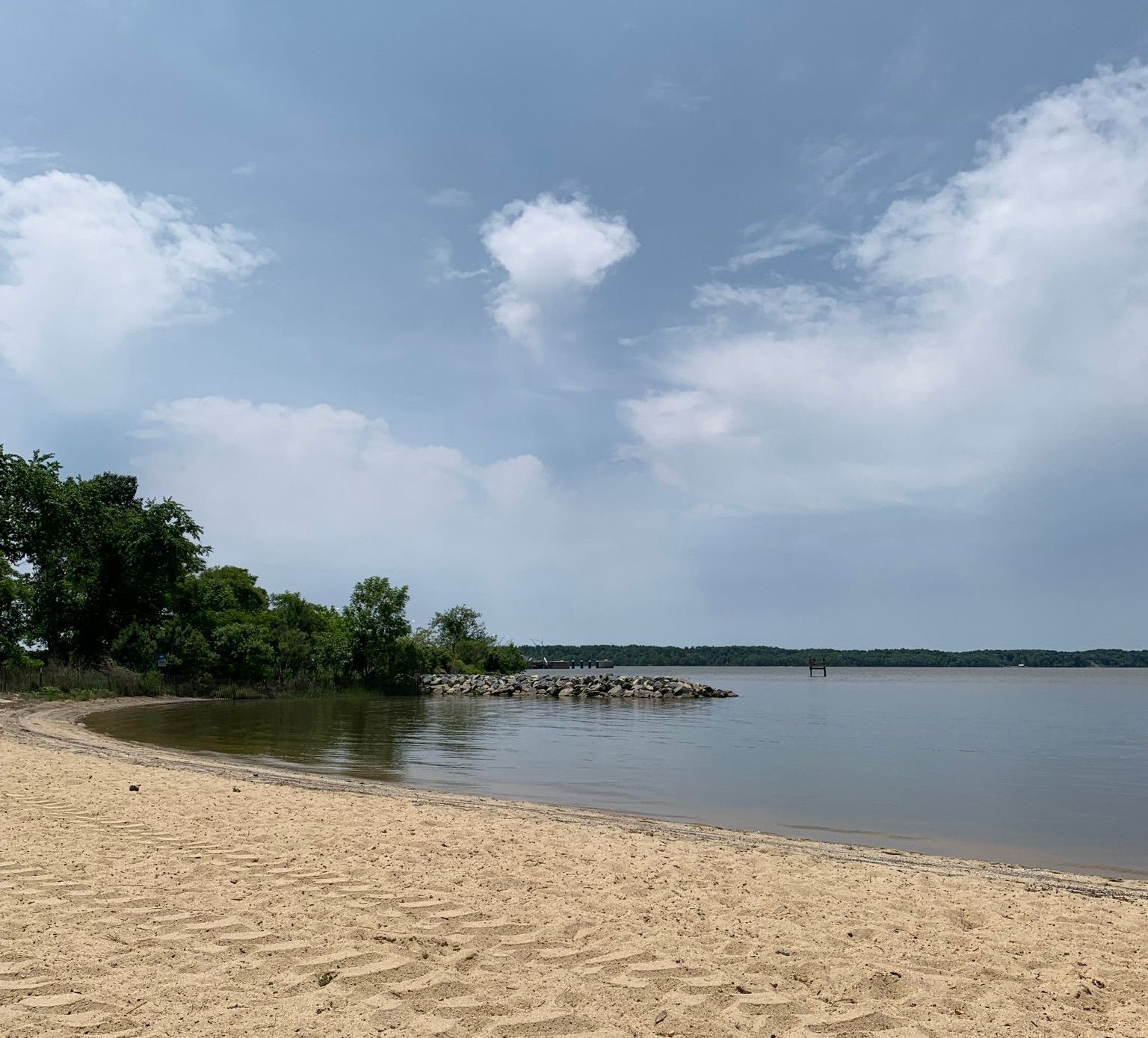 A sandy beach next to a body of water on a cloudy day