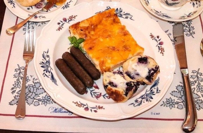 A plate of food with sausages and blueberry muffins on a table