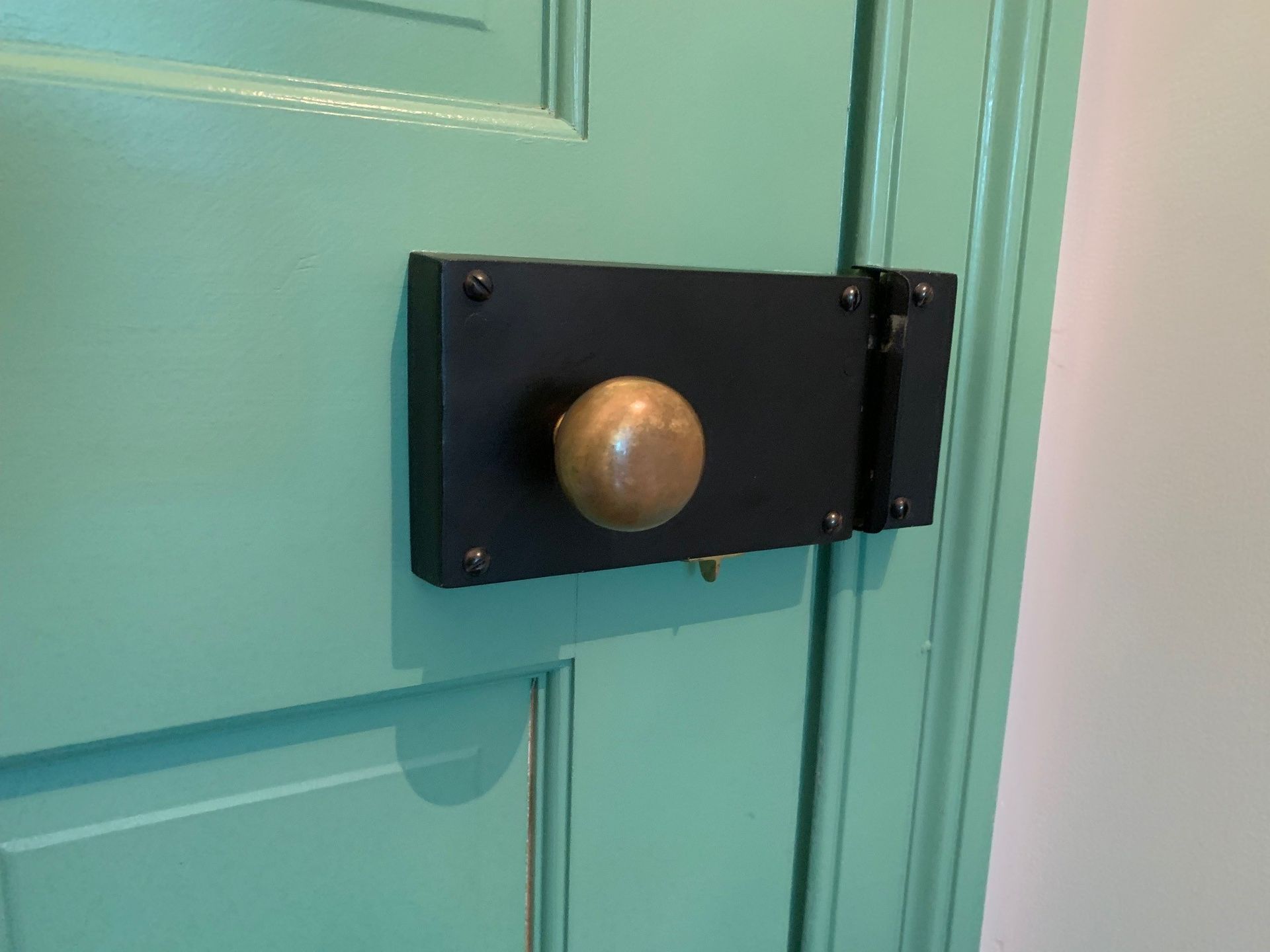 A close up of a door lock on a green door.