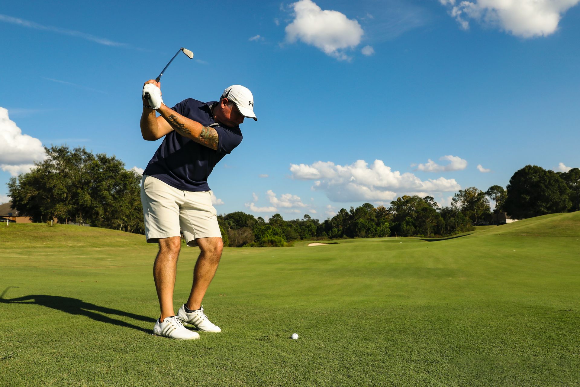 A man is swinging a golf club on a golf course.