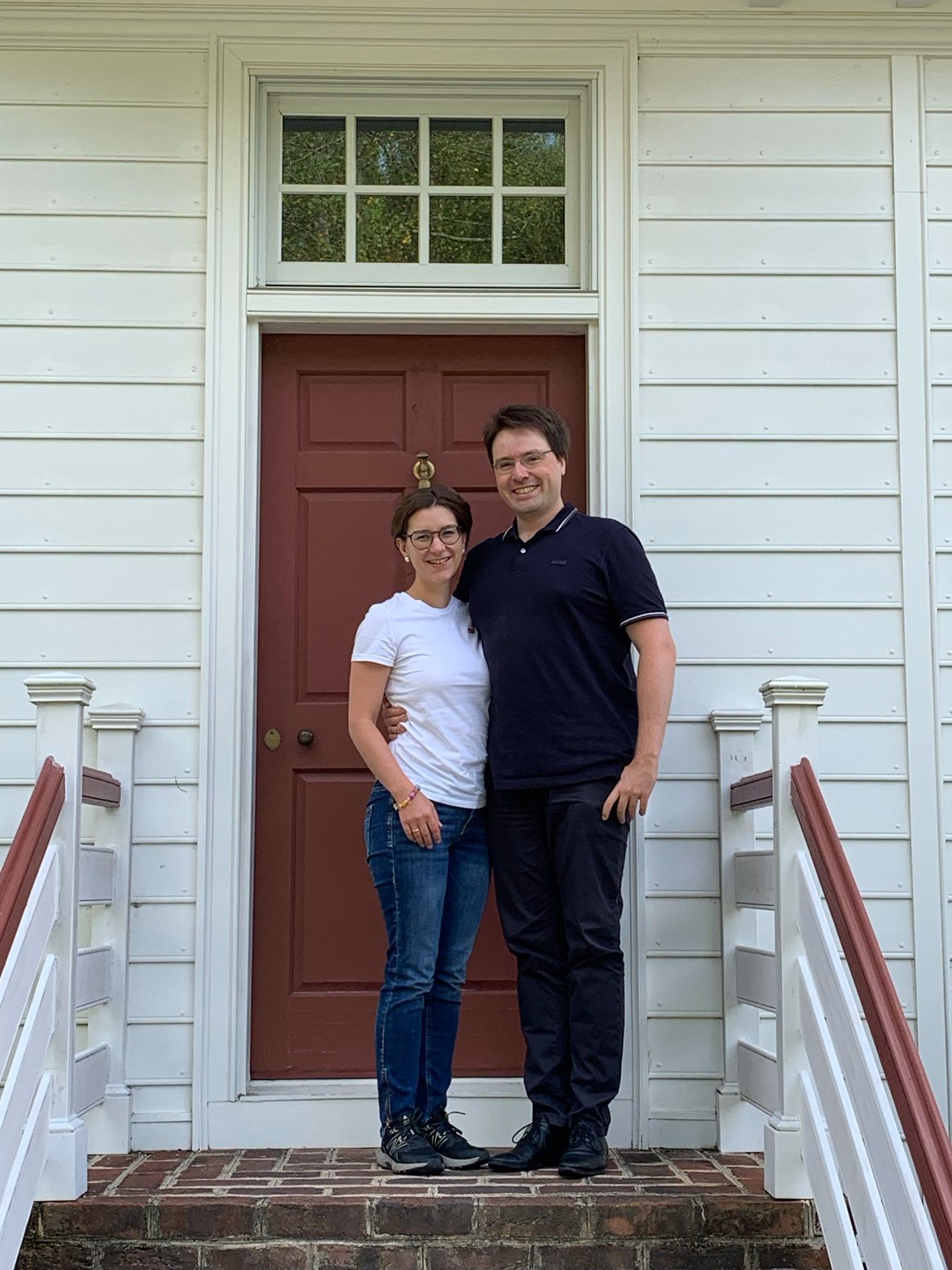 A man and a woman are standing in front of a red door.