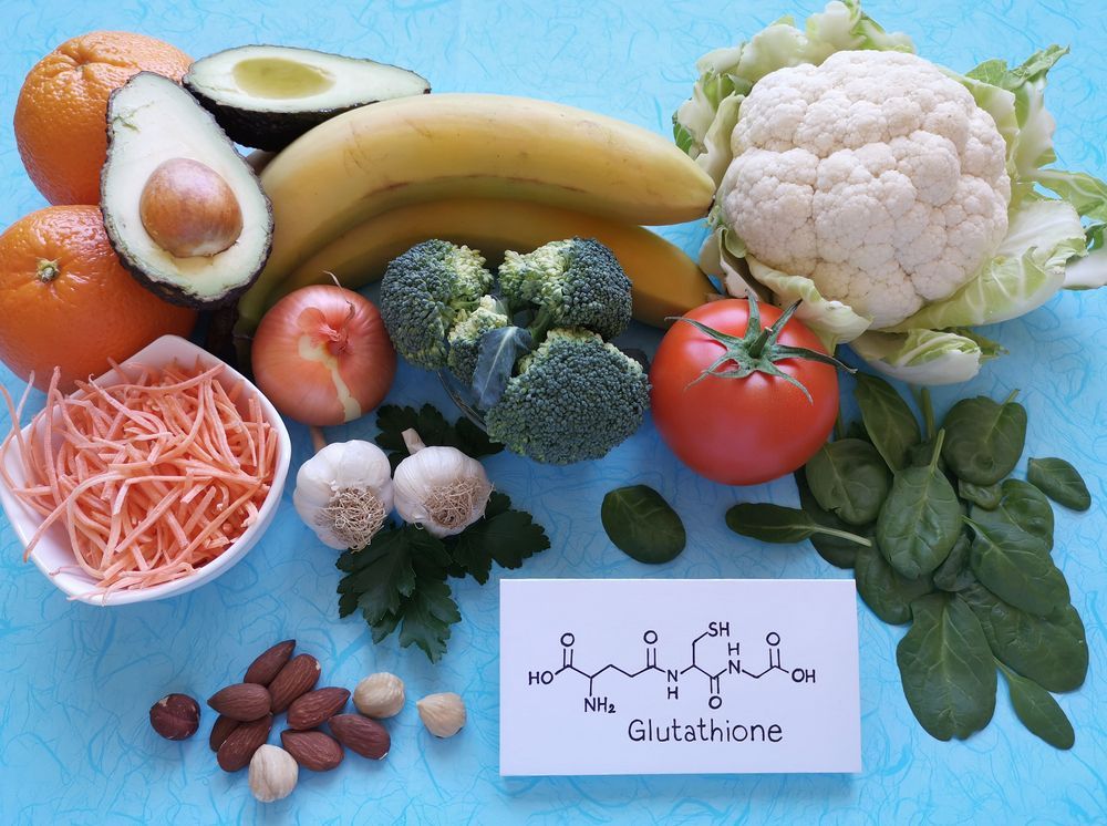 A variety of fruits and vegetables are on a table with a sign that says glutathione.