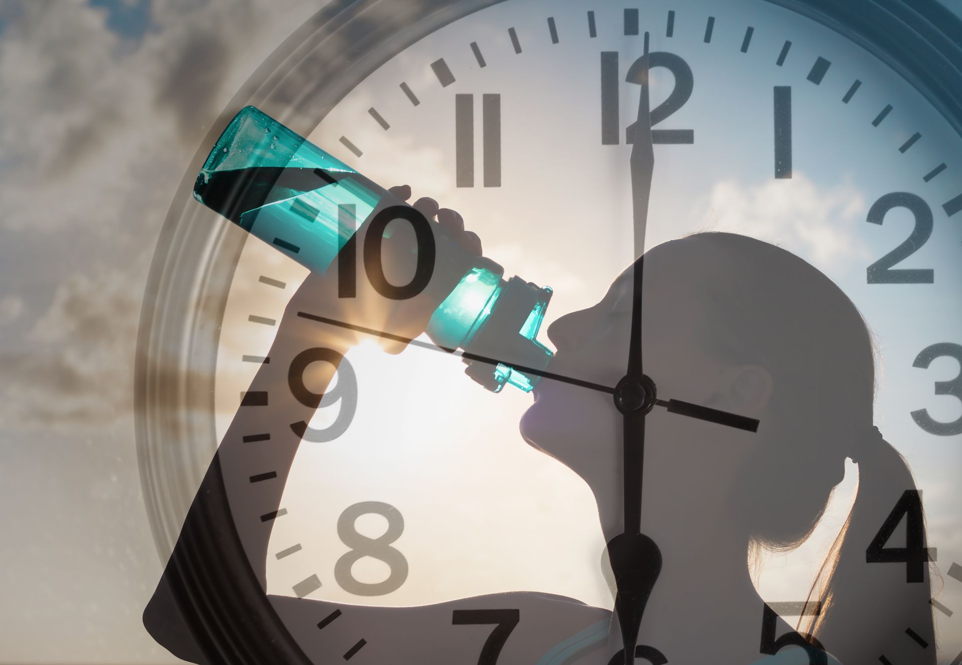 A woman drinking water from a bottle in front of a clock