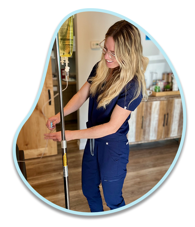 A woman in blue scrubs is standing next to an iv pole