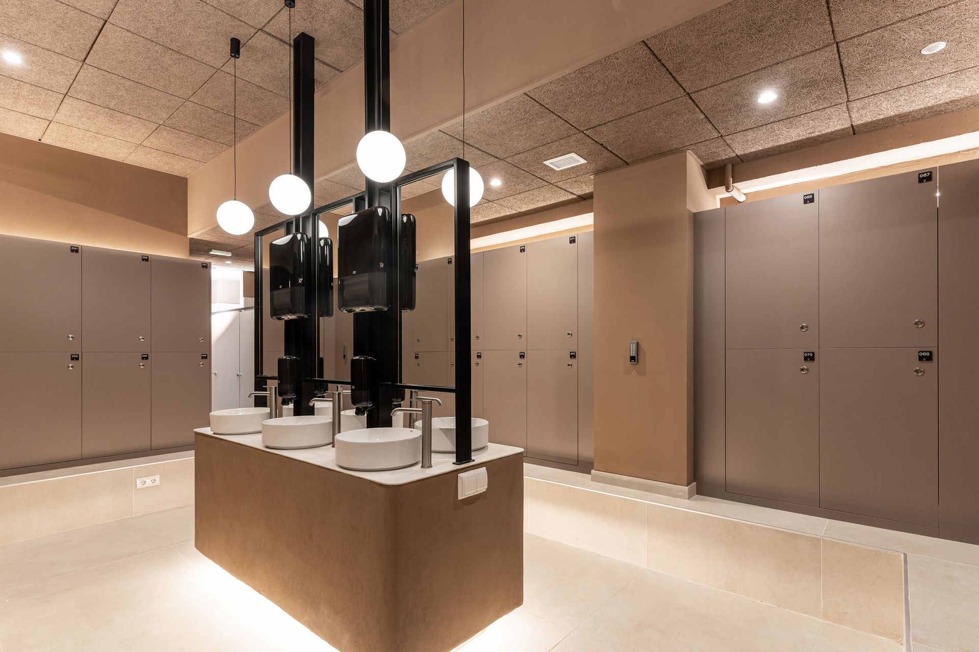 Vestíbulo de hotel moderno con una isla central de mármol, lámparas colgantes y paneles de pared beige.