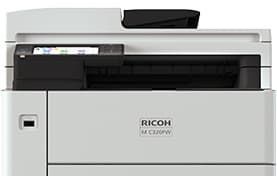 Close-up of a gray Ricoh printer with a black paper tray opening.
