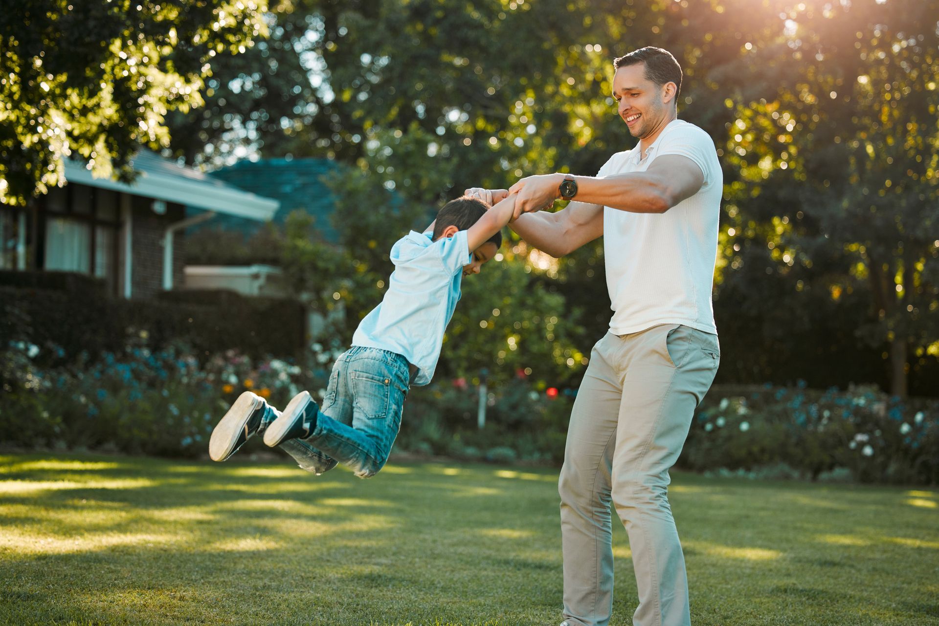 A man and a boy are playing in a park and the boy is jumping in the air.