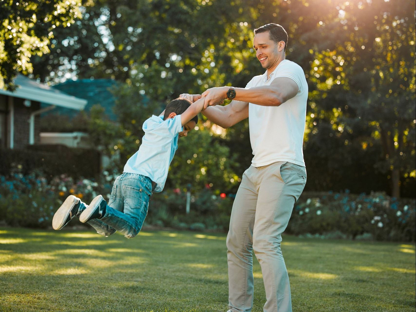 A man is holding a child in the air in a park.