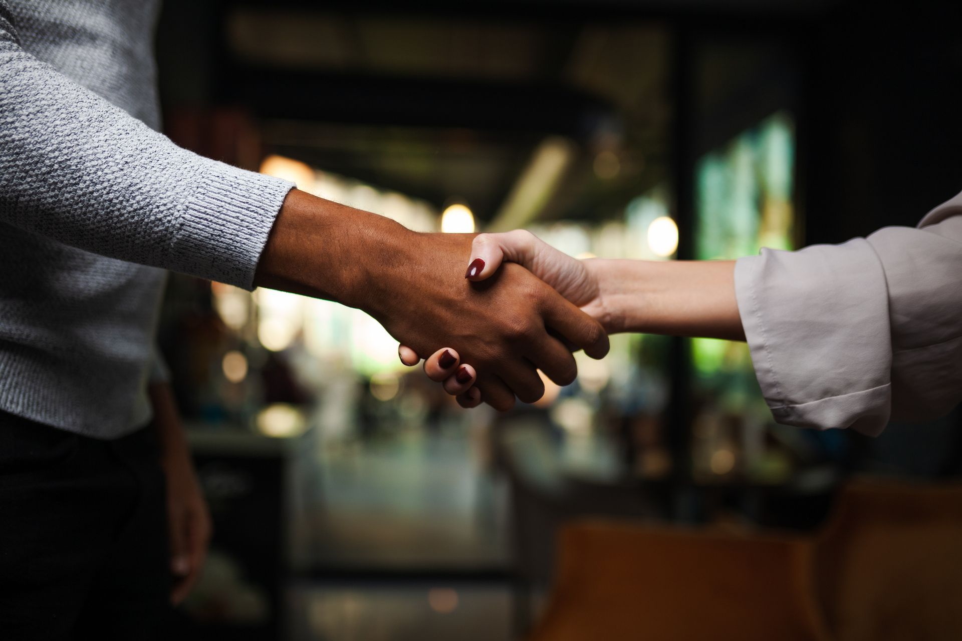 A man and a woman are shaking hands in a dark room.