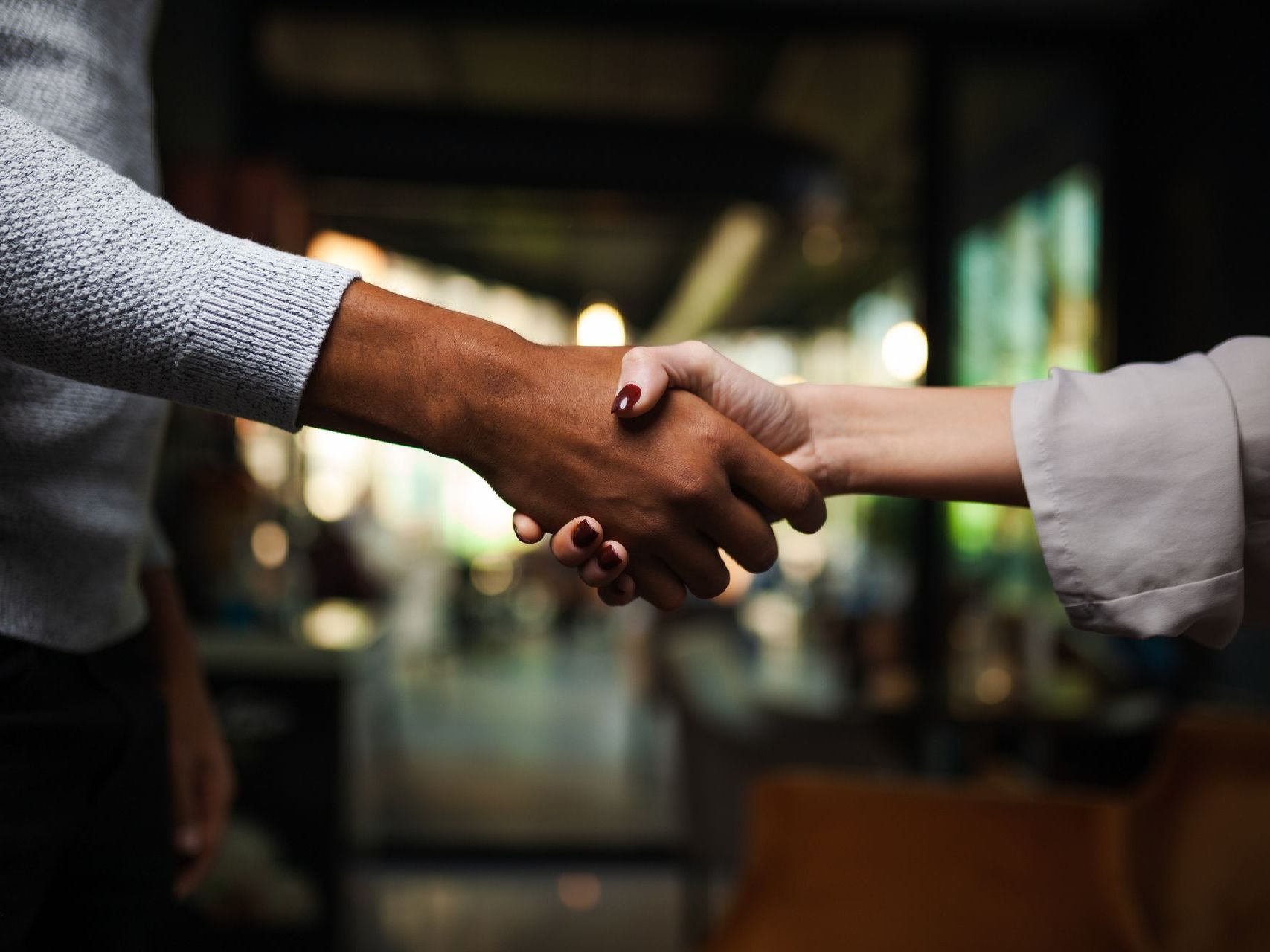 A man and a woman are shaking hands in a restaurant.