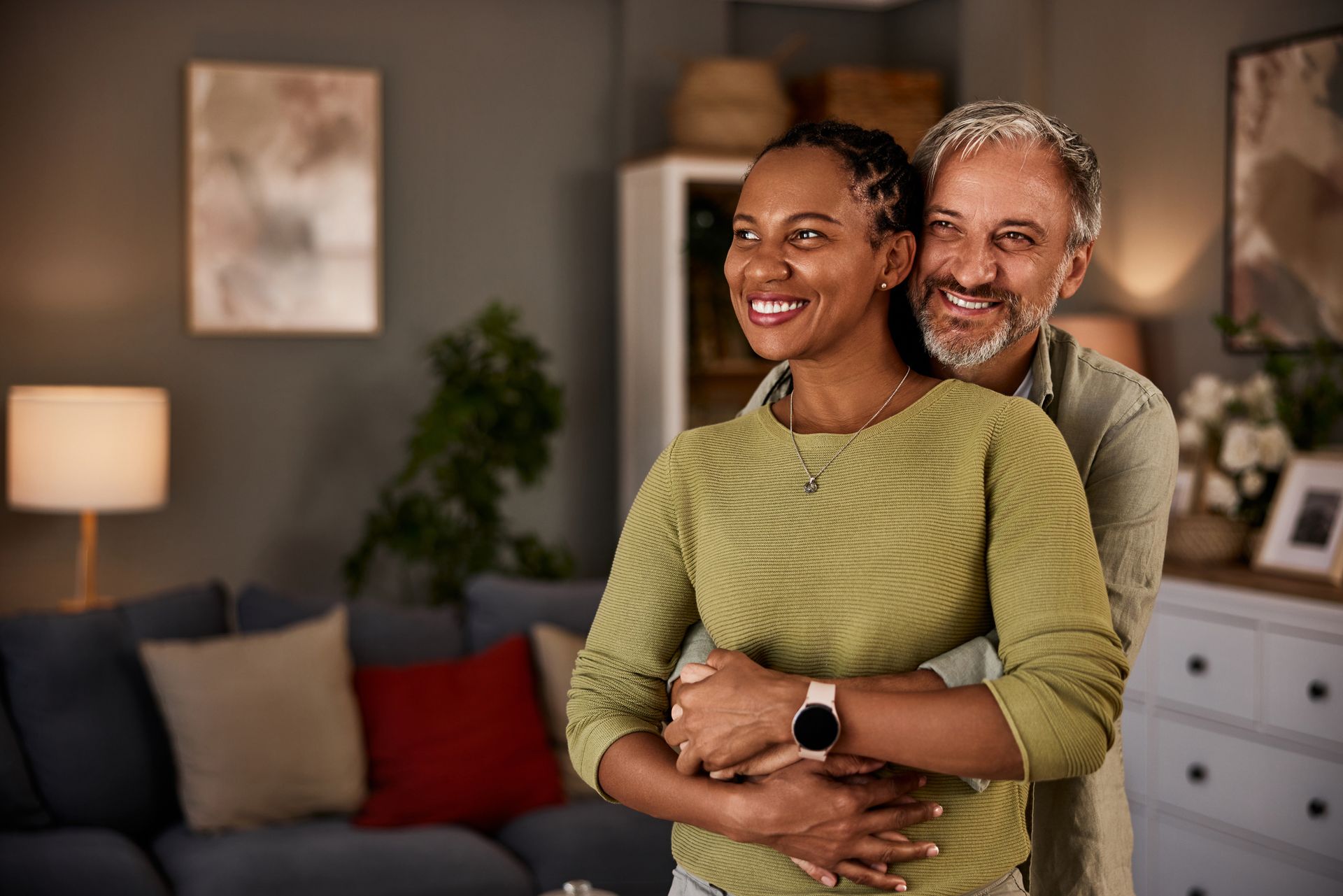 A man and a woman are hugging each other in a living room.