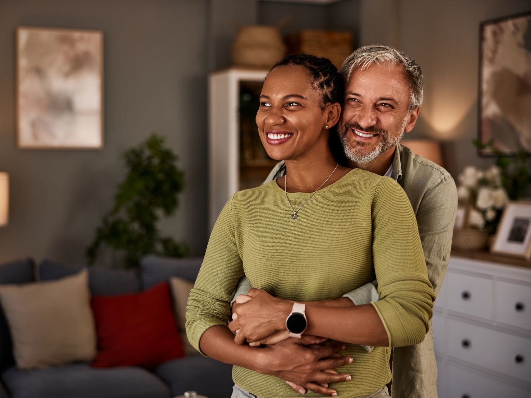 A man and a woman are hugging each other in a living room.