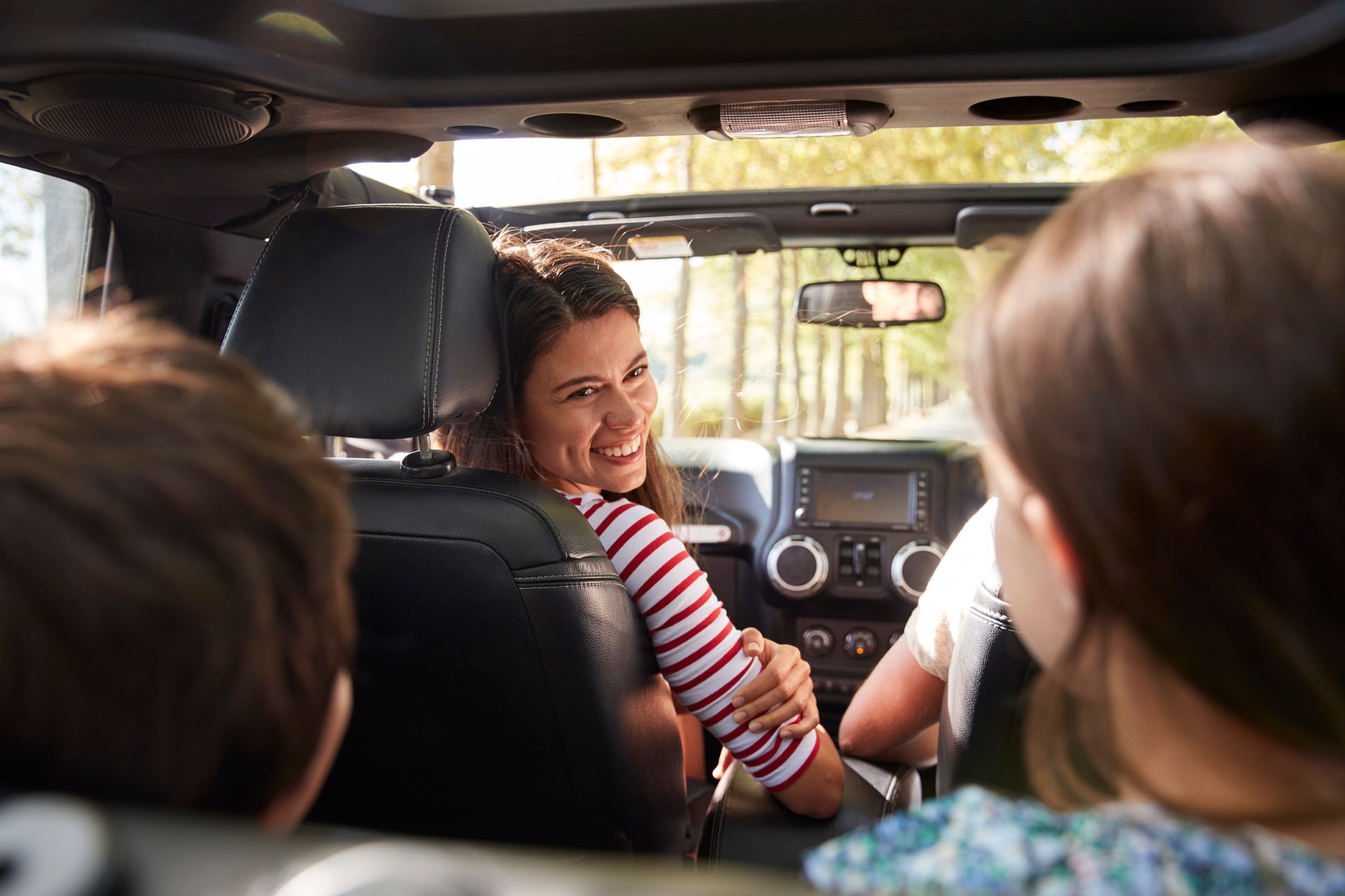 A family is sitting in the back seat of a car.