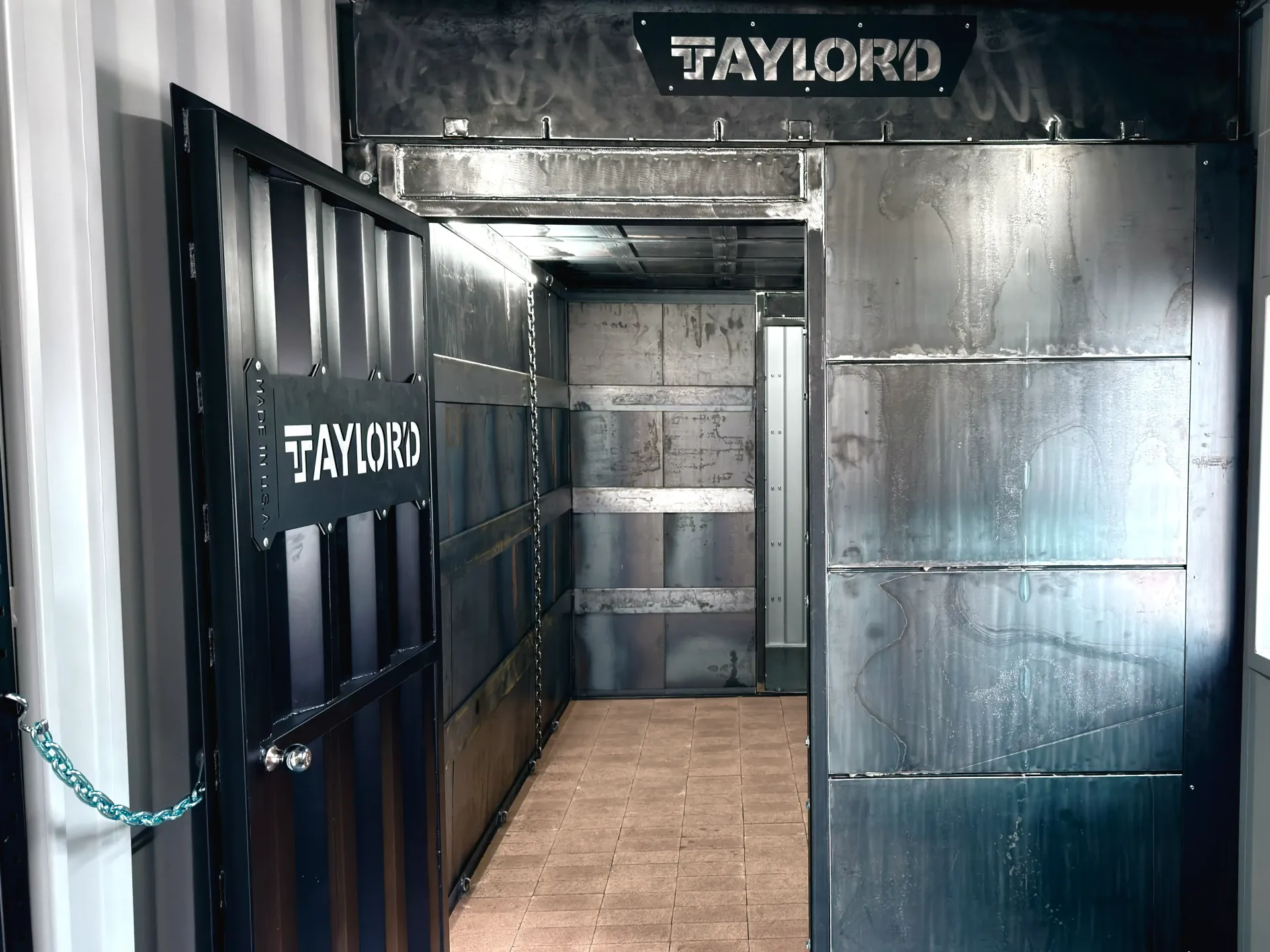 Open black shipping container with “TAYLOR” signage and a metal doorway inside.