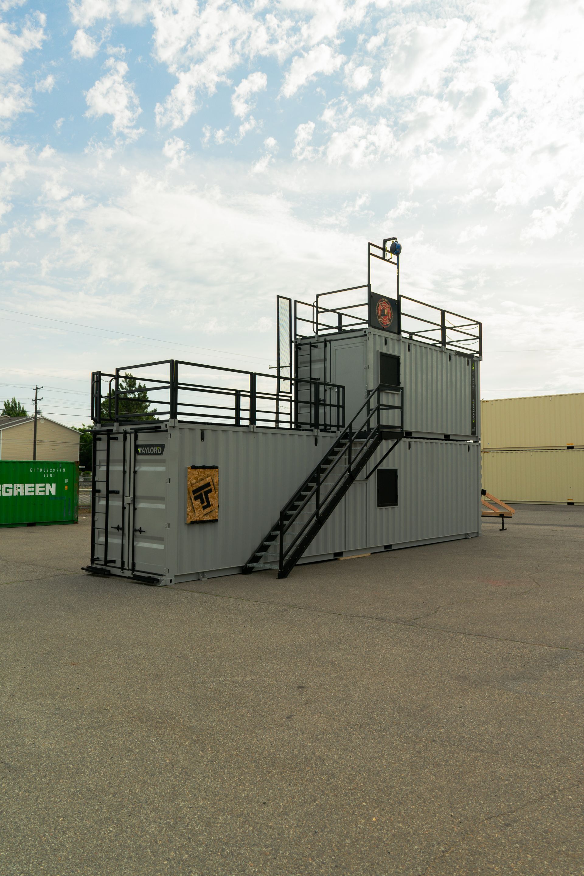 Gray industrial equipment unit with stairs and railings on a gravel lot under a cloudy sky