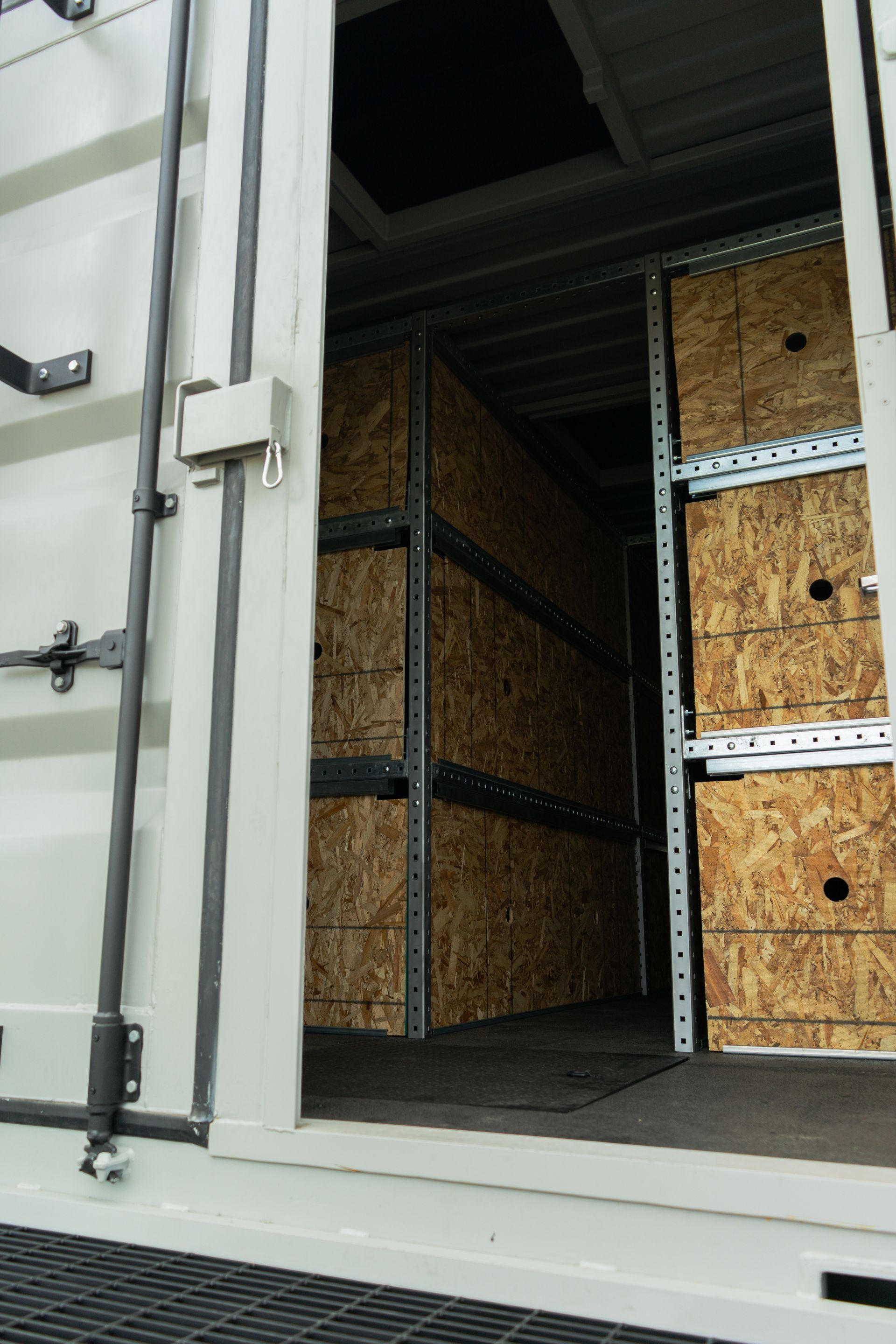 Open shipping container with stacked wooden crates and metal shelving inside