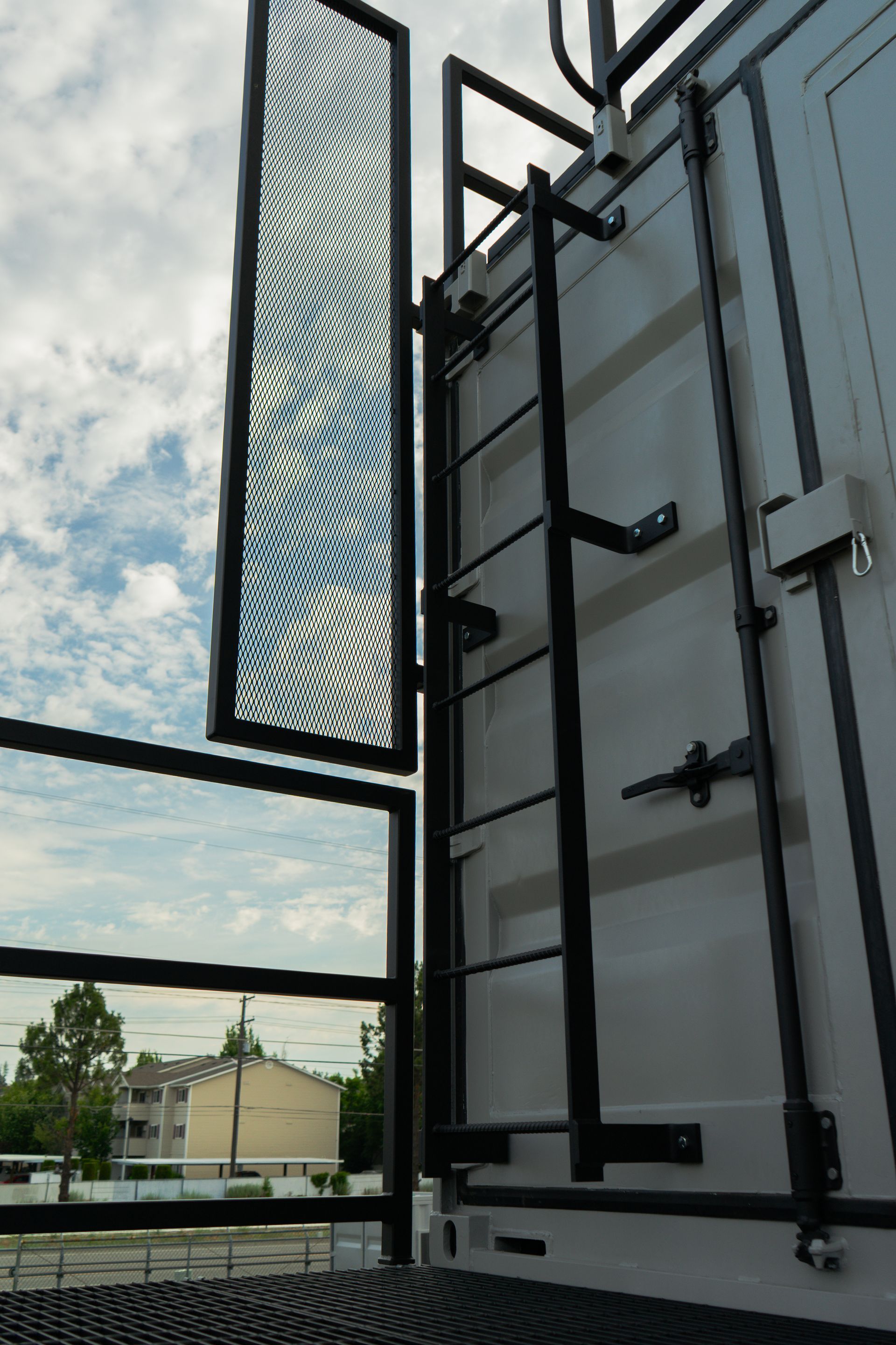 Open metal balcony door with city view and cloudy sky beyond