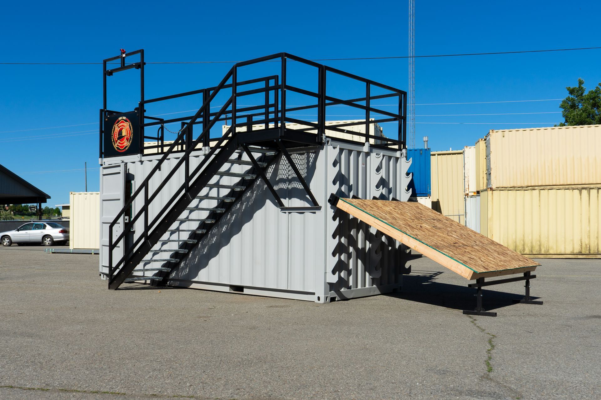 Portable metal stairs and ramp attached to a shipping container in a parking lot under a blue sky
