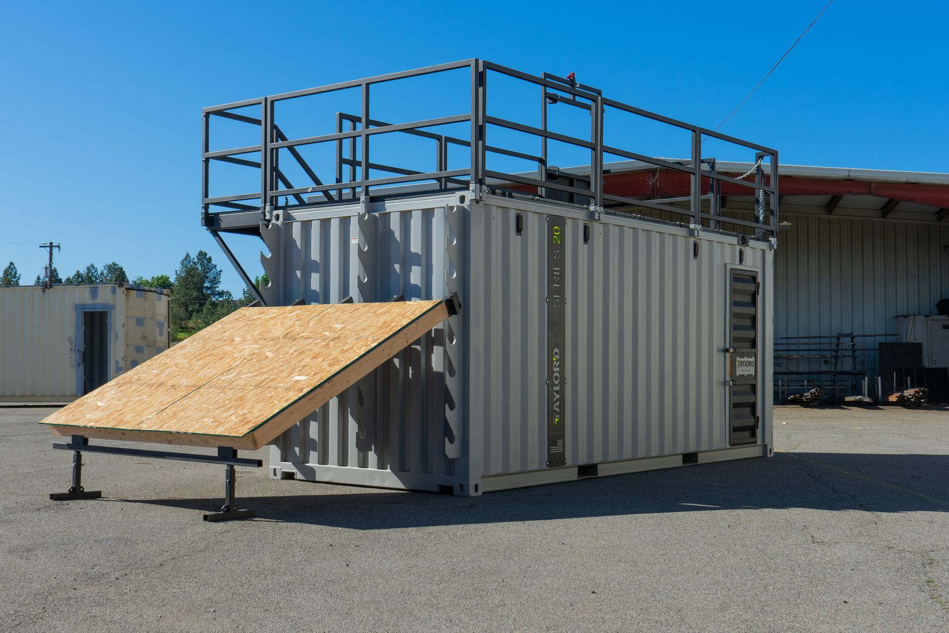 Training container with rooftop railings and a slanted plywood ramp in an outdoor yard