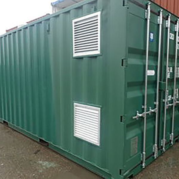 Green shipping container with white vents on a wet pavement